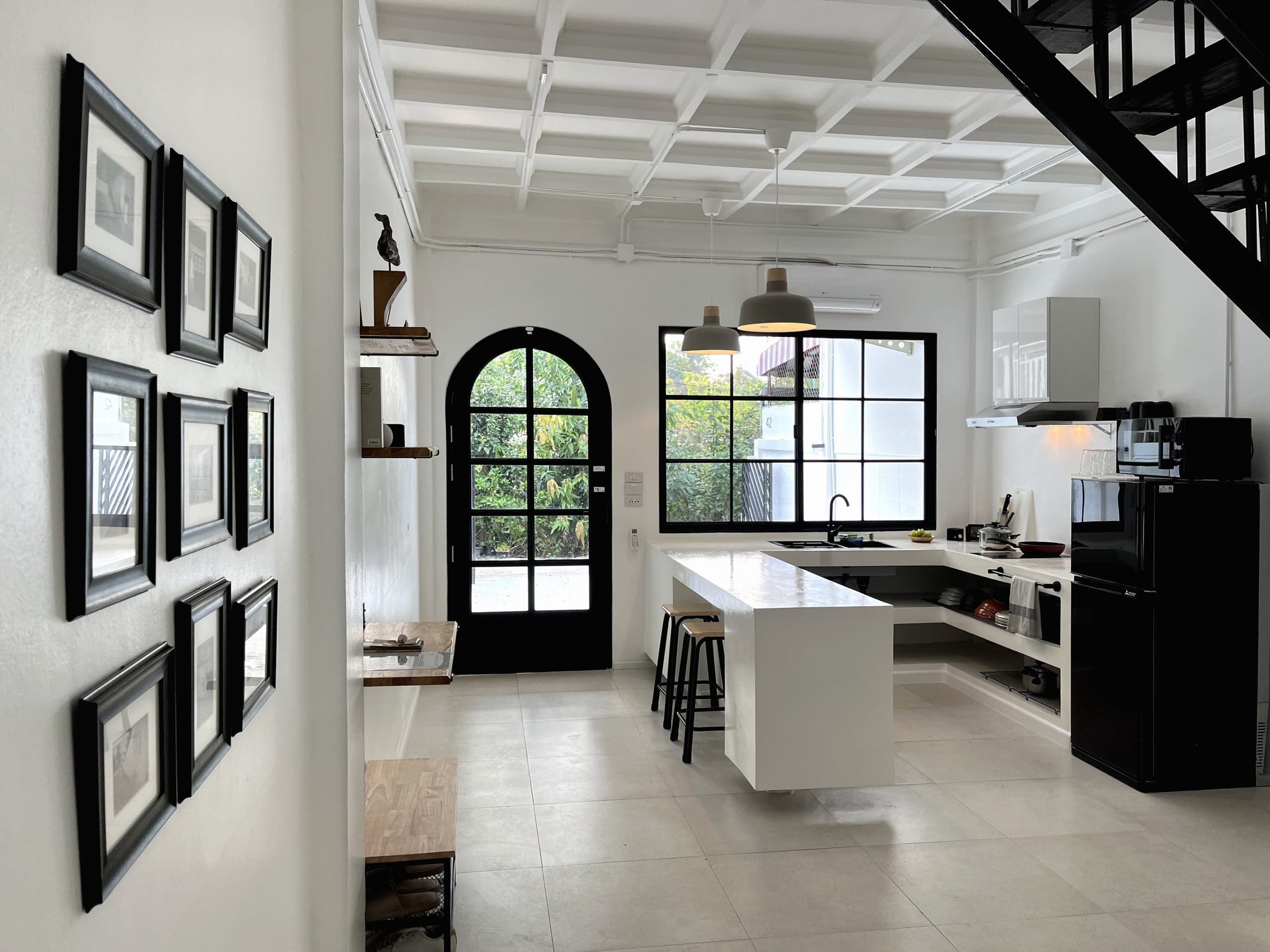 The kitchen from the entry hall, with the island and stools, the arched door to the yard and the stairs on the right